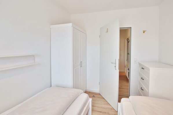 A bedroom with two beds, a wardrobe, and a dresser.