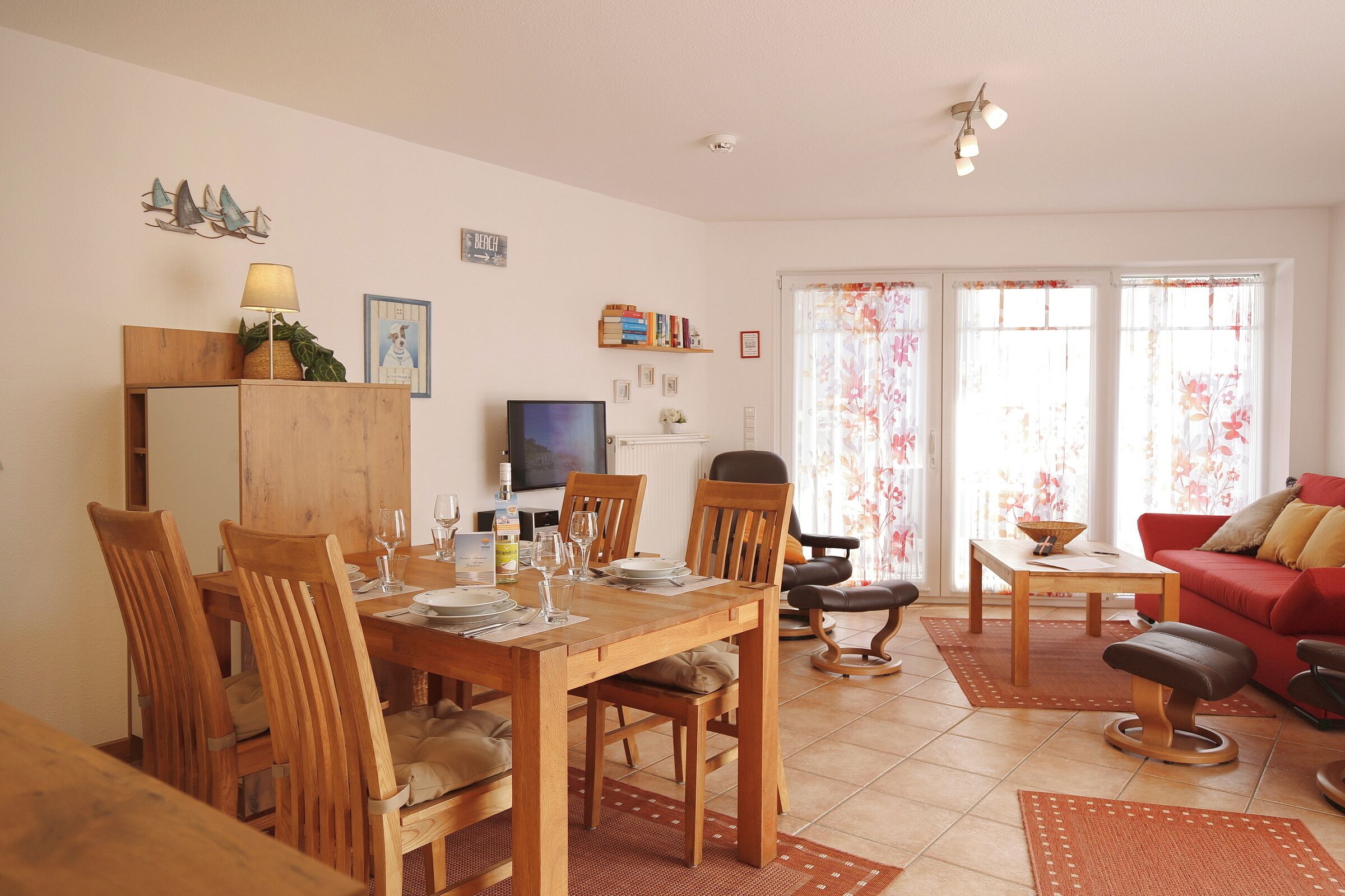 Un comedor con una mesa y sillas de madera, un televisor y un sofá rojo.