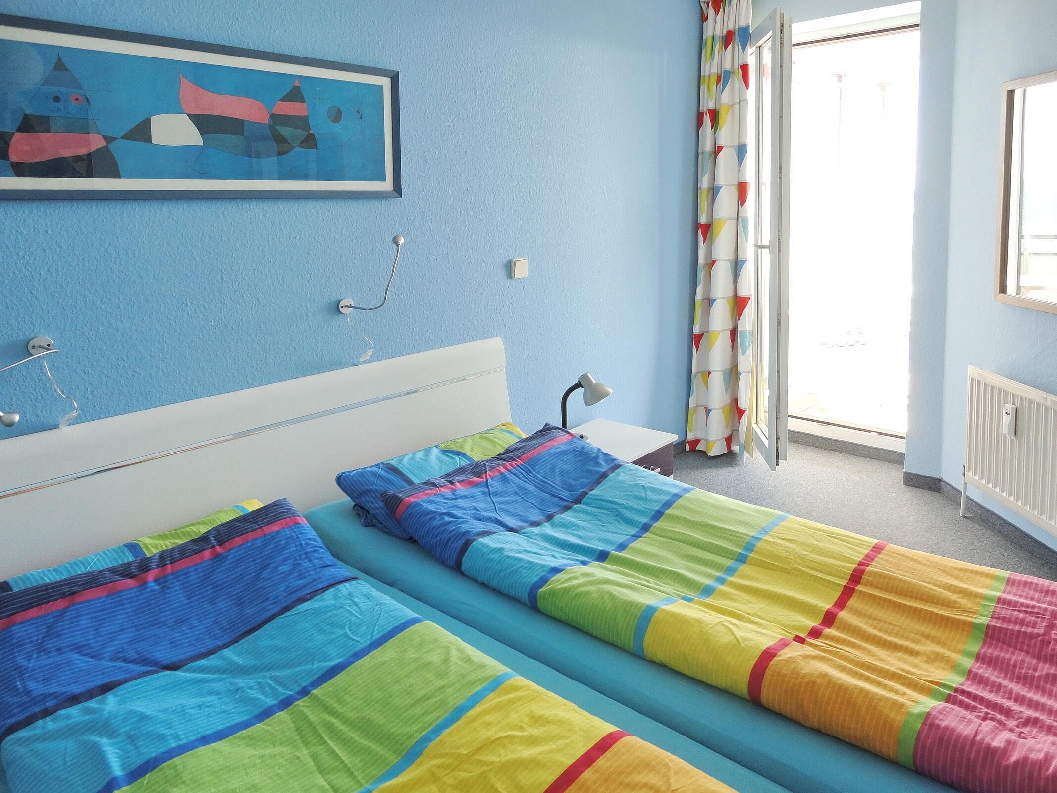 Une chambre avec deux lits, un bureau, une lampe et une fenêtre avec des rideaux.