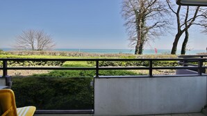 A balcony with a view of the sea, a chair, and a railing. - Residenz am Hang Appartement 103 (Scharbeutz)