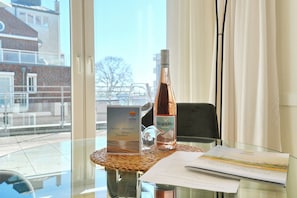 A glass table with a bottle of wine, a glass, a menu, and a welcome card.
