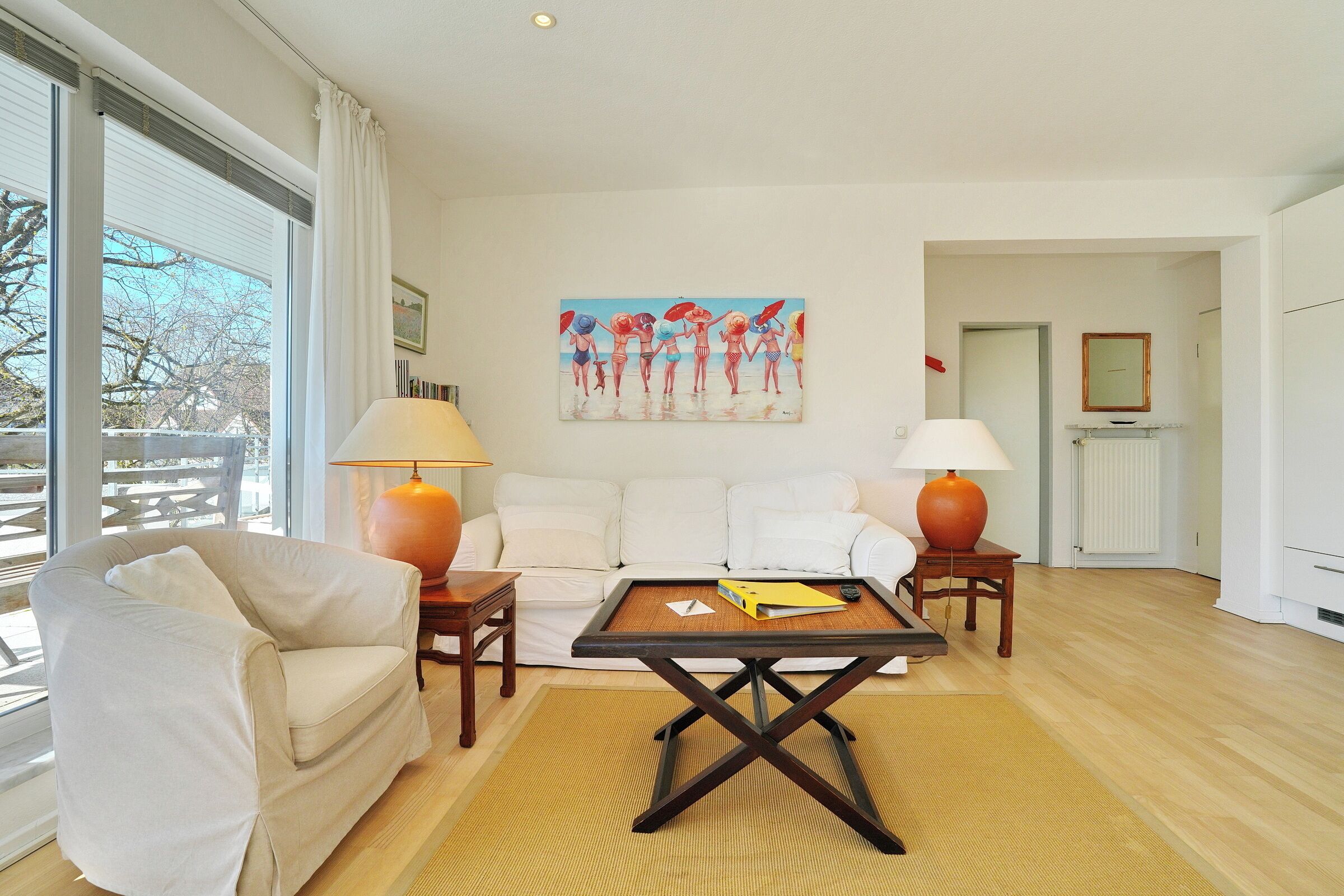 A living room with a white sofa, a wooden coffee table, and two lamps.