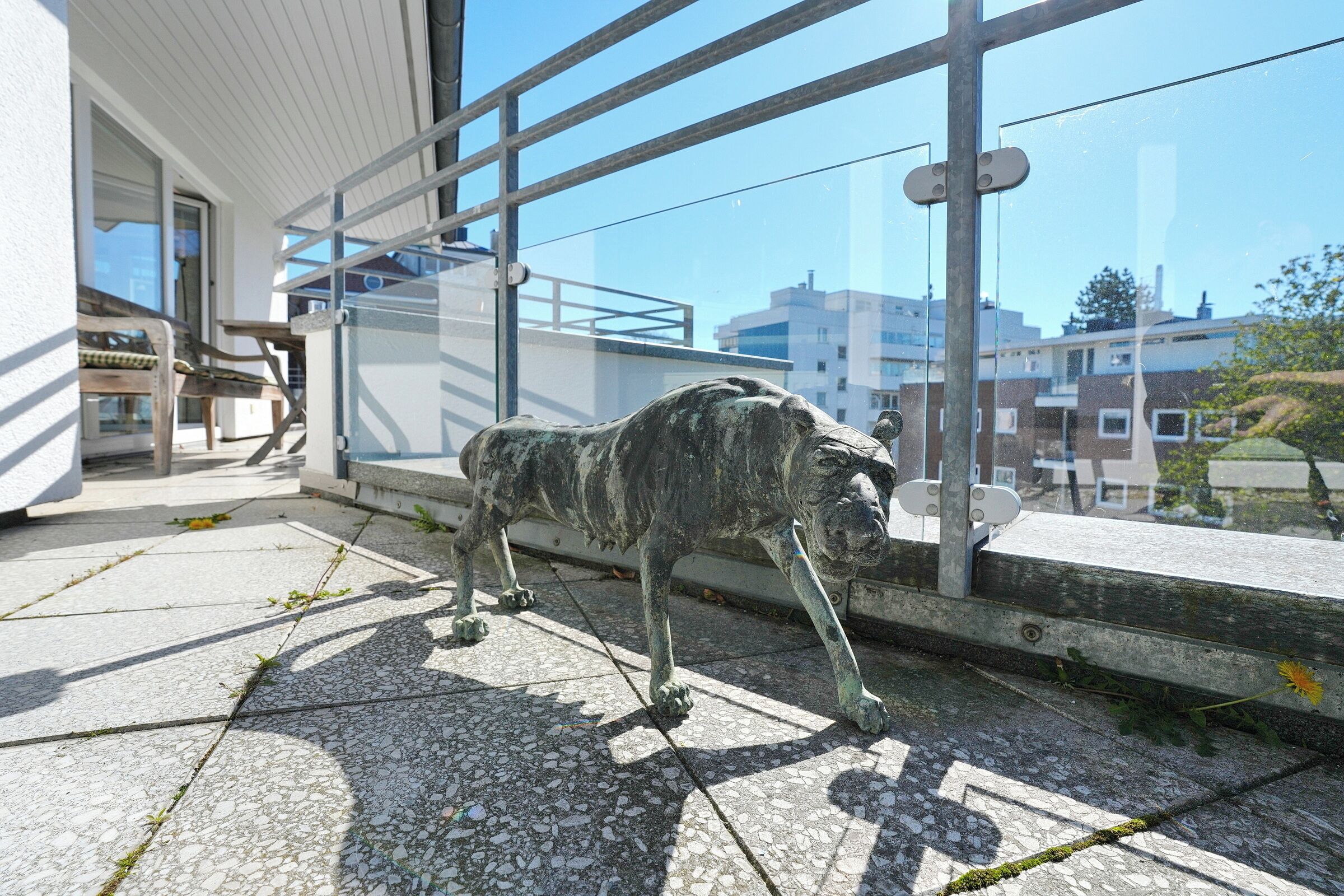 A statue of a dog on a balcony with a view of buildings.