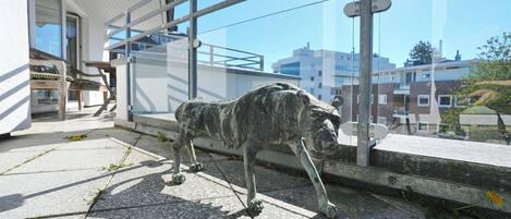 A statue of a dog on a balcony with a view of buildings.