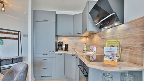 A modern kitchen with grey cabinets, a wooden countertop, and a built-in oven. - Berliner Hof Appartement 116 (Scharbeutz)
