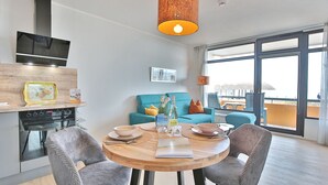 A modern kitchen with a built-in oven and a dining area with a round wooden table and four chairs. - Berliner Hof Appartement 116 (Scharbeutz)