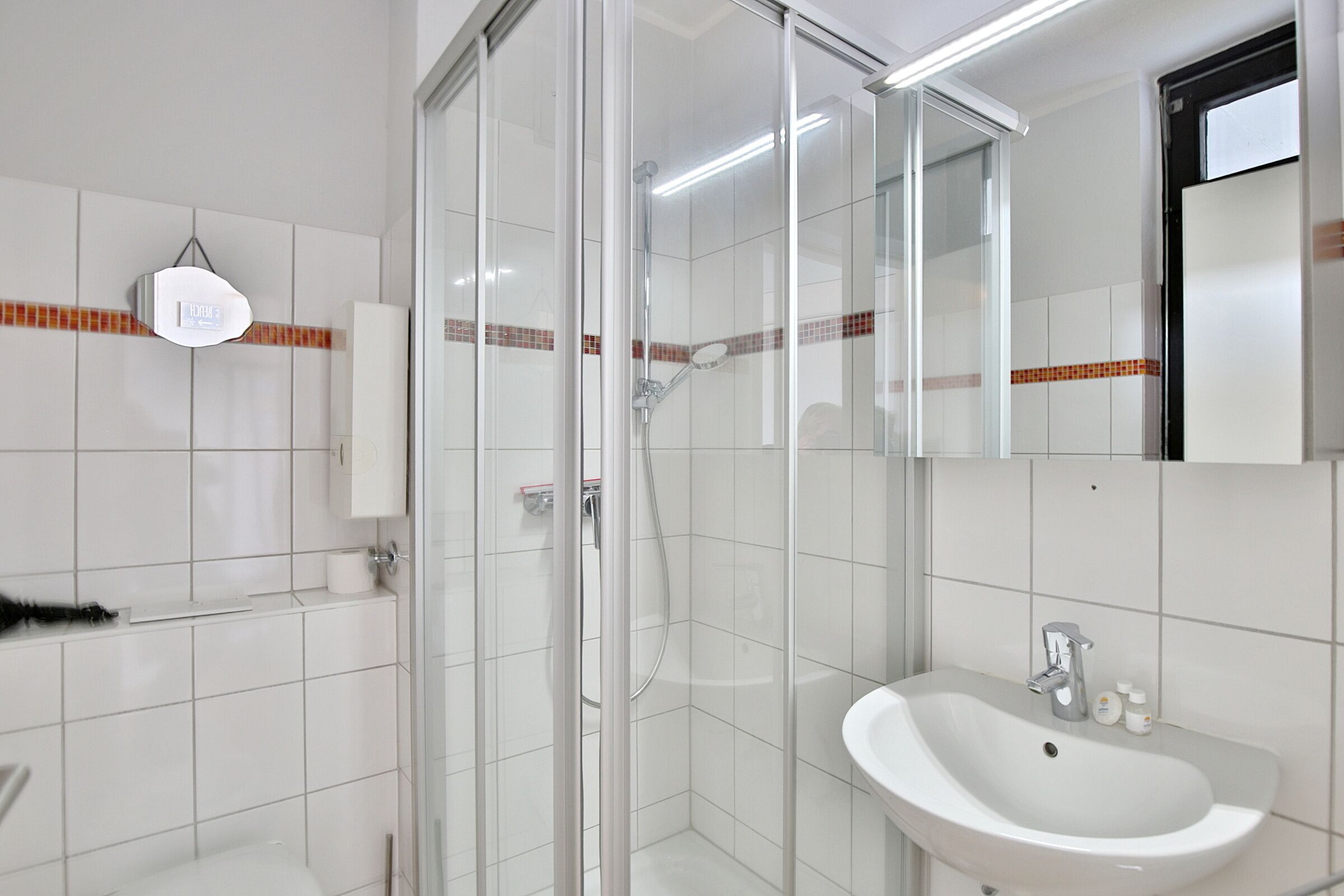 Une salle de bain moderne avec une douche à parois de verre, un lavabo blanc et un miroir.