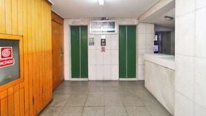 A hallway with wooden paneling on one side, green doors, and a tiled floor. - Rio Spot Homes C039 (Rio de Janeiro)