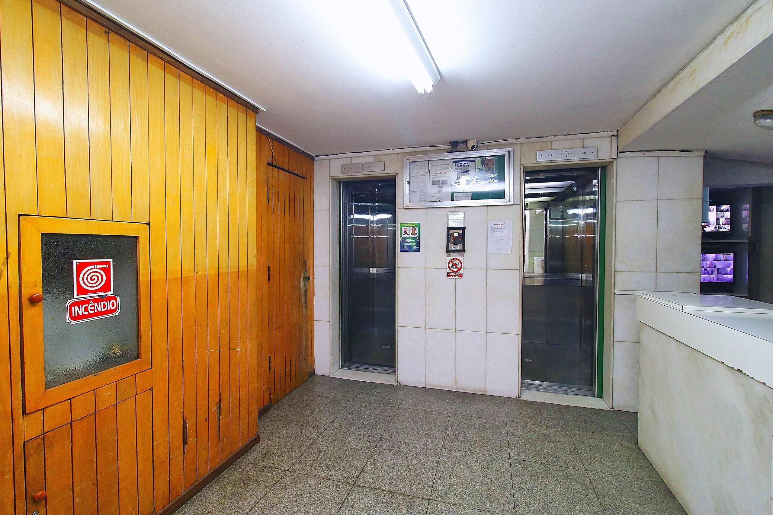 A hallway with wooden paneling, two elevators, and a reception desk.