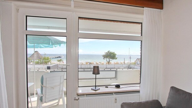 Una stanza con vista sul mare, una sedia bianca, un tavolo e una lampada.