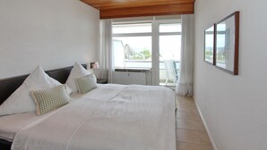 Una camera da letto con un letto grande, due cuscini, un comodino, una finestra con vista e un quadro appeso al muro.