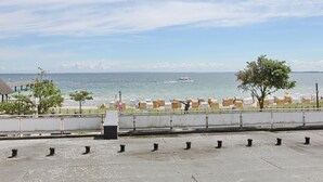 Vista sulla costa con cielo sereno, un tratto d'acqua e una fila di barili gialli sulla riva.