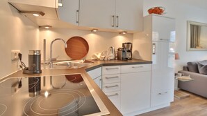 A modern kitchen with a built-in stove, white cabinets, and a coffee maker.