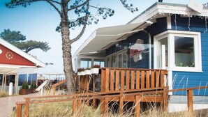 A coastal building with a wooden deck, a covered porch, and a large window.