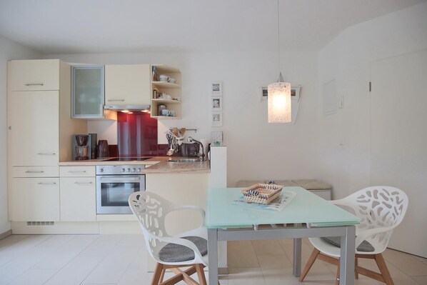 Une cuisine compacte avec un coin repas, comprenant une table avec des chaises, une machine à café et un réfrigérateur.