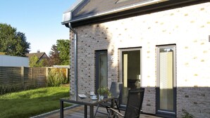 A patio with a table and chairs, a brick wall, and a door leading to an interior space. - Haus Küstenkinder Louis Appartement 2 (Scharbeutz)