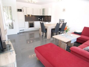 Una cocina moderna con armarios blancos, encimera negra y un comedor con mesa y sillas de madera.