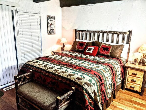 A bedroom with a bed, a nightstand, a chair, a window with blinds, and a wall with a poster.