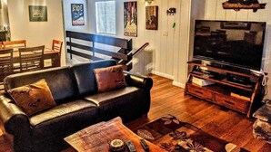 A living room with a sofa, coffee table, and a TV stand. There is a staircase leading to another level. - Ski, Soak & Relax, 2 BR/1.5 BA Townhouse with Spa, at the base of Snow Summit (Big Bear Lake)