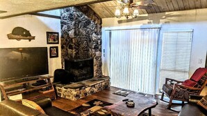 A cozy living room with a stone fireplace, leather sofas, a flat-screen TV, and a wooden coffee table. - Ski, Soak & Relax, 2 BR/1.5 BA Townhouse with Spa, at the base of Snow Summit (Big Bear Lake)