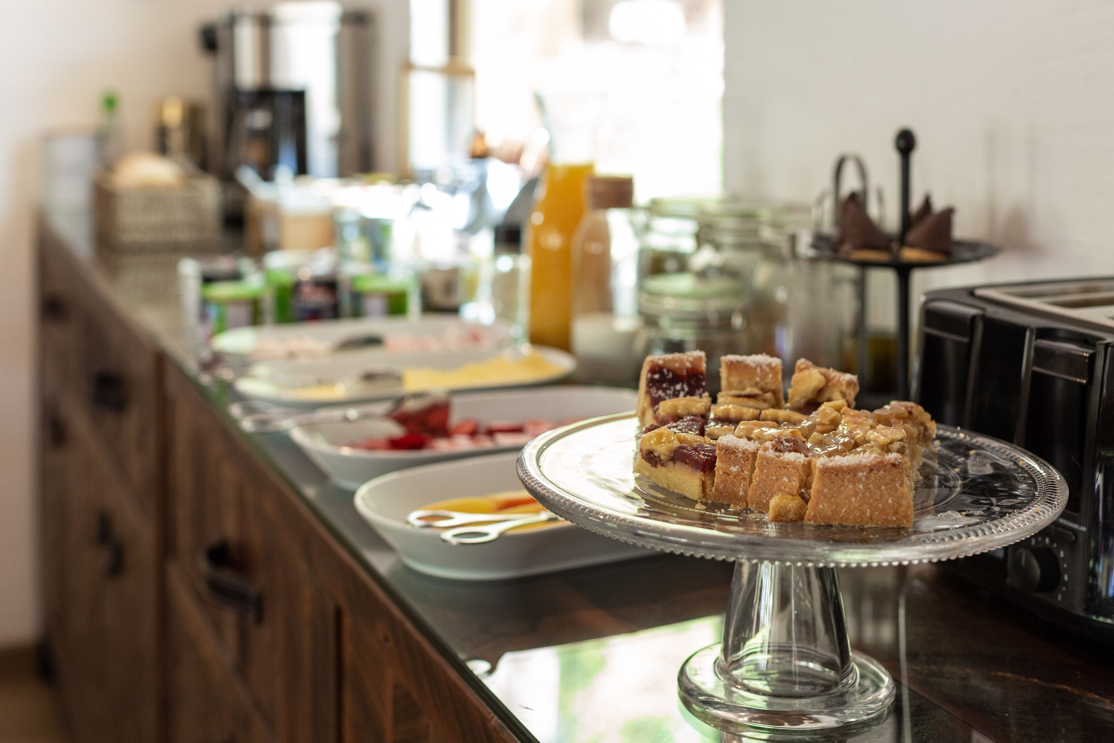 Un mostrador de buffet con diversos alimentos y un expositor de vidrio para pasteles.