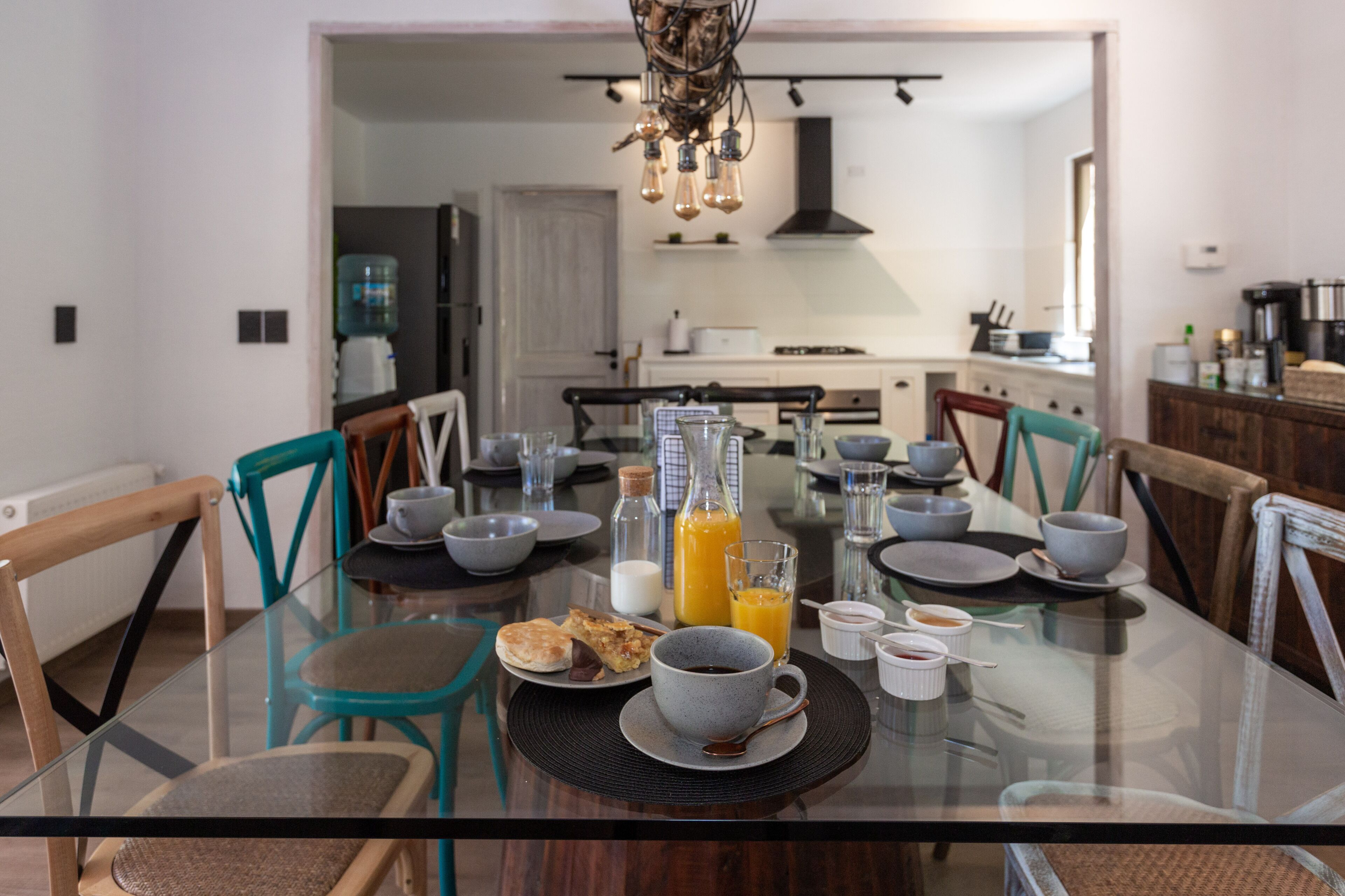 A dining table set with breakfast items, including a glass of orange juice, a cup of coffee, and plates with food.