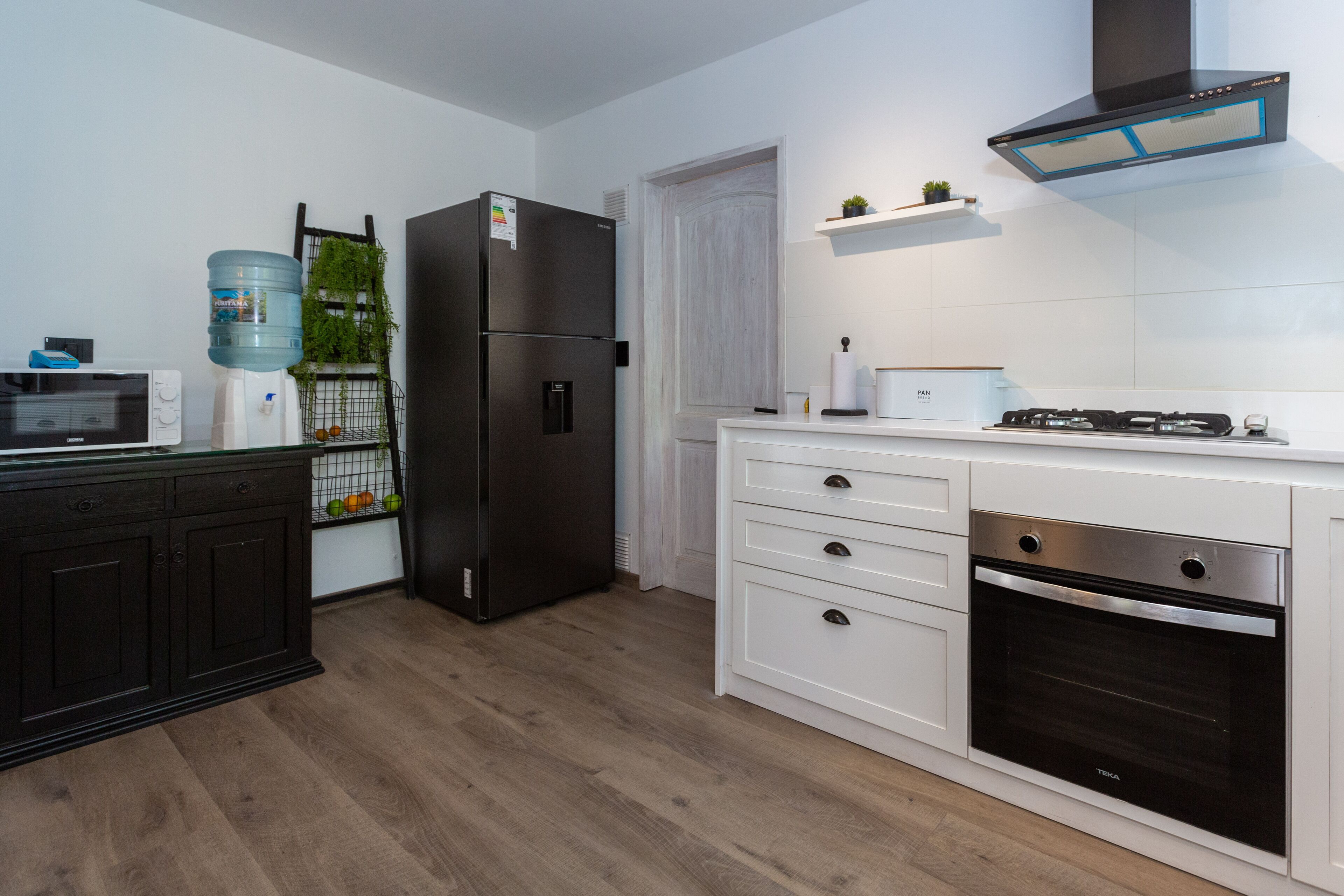 A modern kitchen with a stainless steel refrigerator, built-in oven, and white cabinetry.