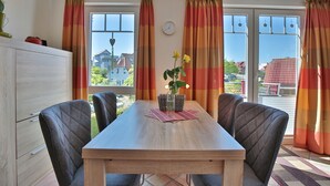 Un comedor con una mesa de madera, cuatro sillas grises tapizadas y un florero con flores sobre un mantel individual.