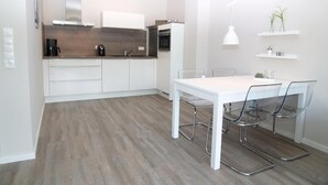 Una cucina moderna con mobili bianchi, un piano di lavoro in legno e un forno integrato.