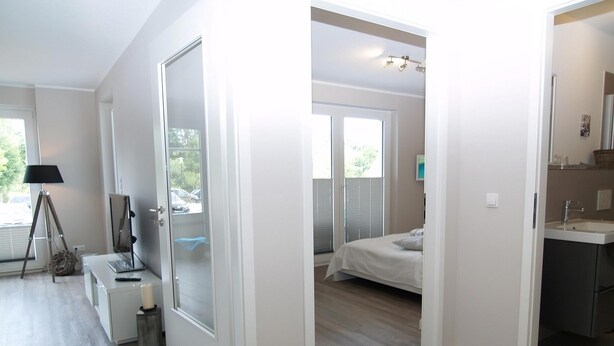Una camera da letto moderna con un letto, un comodino, una lampada e una finestra.