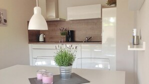 Una cucina moderna con mobili bianchi, un lavandino in acciaio inossidabile e una lampada a sospensione.
