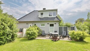 A two-story house with a patio area featuring outdoor furniture and a grill. - Ferienhaus Ragna Appartement 1 (Haffkrug)