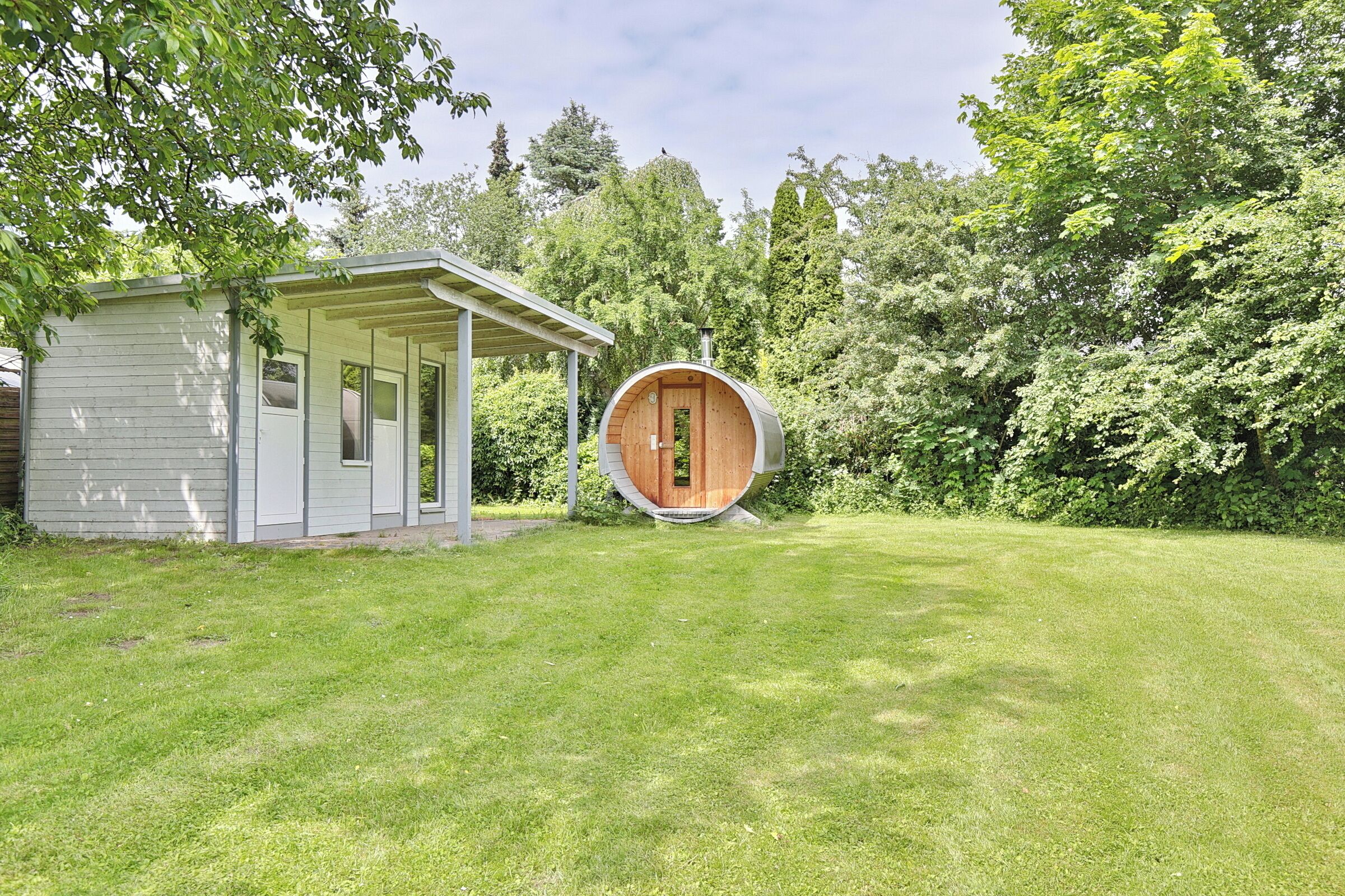 A small, single-story building with a covered porch and a circular wooden structure.