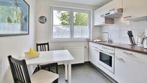 Una cucina compatta con mobili bianchi, forno integrato e una finestra con tende.