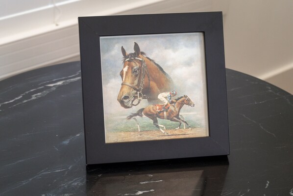 A framed picture of a horse and jockey on a dark marble surface.