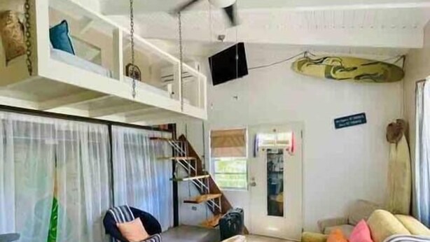 A living room with a ceiling fan, a sofa, a coffee table, and a staircase leading to an upper level.