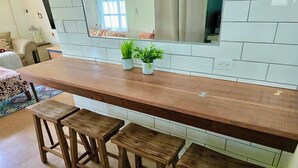 A kitchen with a wooden countertop, three wooden stools, and two potted plants.