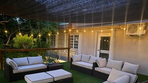An outdoor patio with wicker furniture, artificial grass, and string lights.