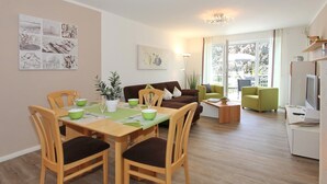 Un salon moderne avec un coin repas, comprenant une table à manger en bois, des chaises, un canapé et un téléviseur.