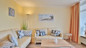 Un salon avec un canapé beige, une table basse en bois et un tableau accroché au mur.