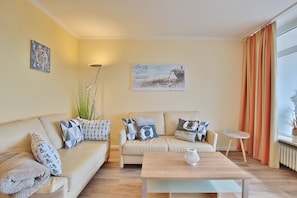 Un salon avec un canapé beige, une table basse en bois et un tableau accroché au mur.