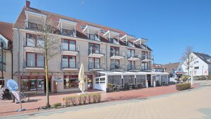 Een hotel met meerdere verdiepingen, balkons, een overdekt terras en een heldere lucht.