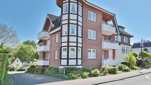 A multi-story residential building with a corner section featuring a bay window. - Parkblick Appartement 4 (Scharbeutz)