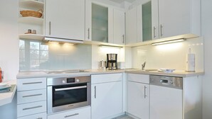 A modern kitchen with white cabinetry, stainless steel appliances, and under-cabinet lighting. - Parkblick Appartement 4 (Scharbeutz)