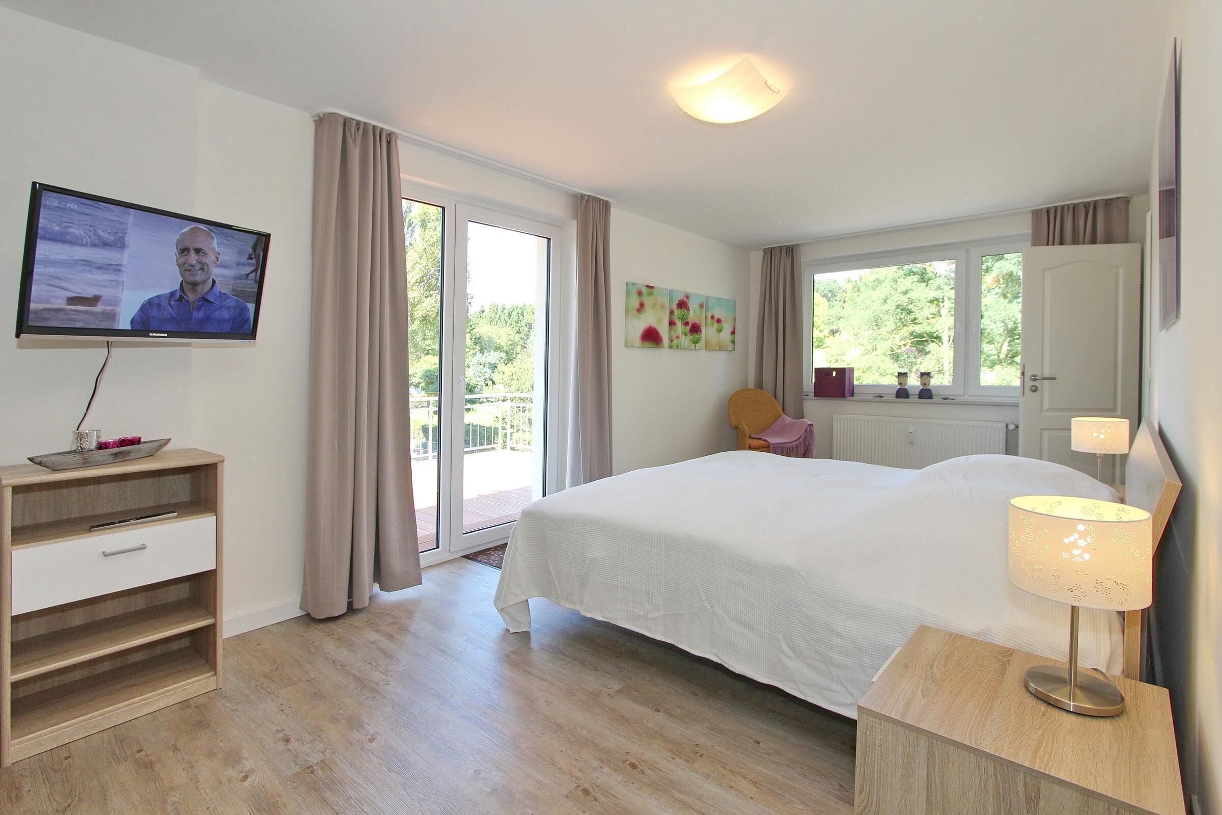 A bedroom with a bed, a TV, a desk, and a chair.