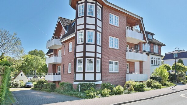 A multi-story residential building with a corner section featuring a bay window.