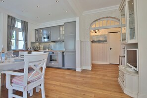 Una cocina moderna con armarios grises, una mesa de comedor con sillas y piso de madera.