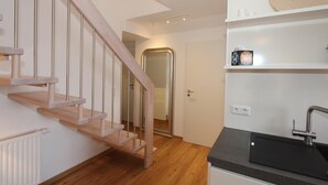 A modern kitchen with a wooden staircase, a black countertop, and a built-in sink. - Domizil am Möwenberg Appartement 9 (Scharbeutz)