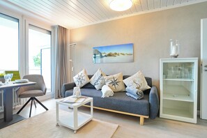 A modern living room with a grey sofa, a coffee table, and a cabinet with glass doors.