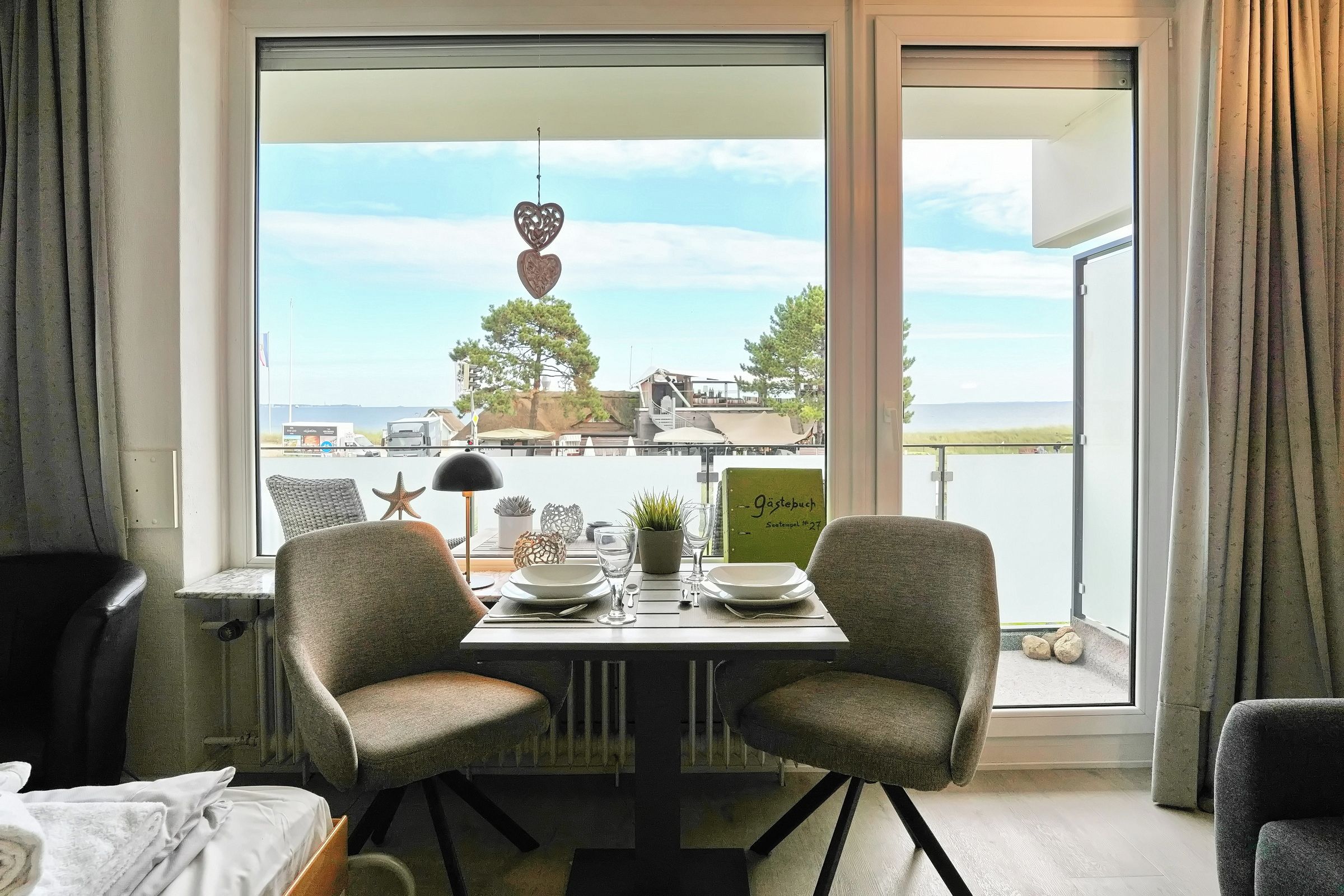 Een eetgedeelte met twee stoelen, een tafel en uitzicht op een kustlandschap.